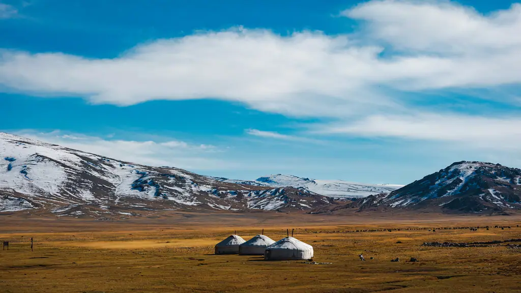 Three gers in a wide valley beneath snow-dusted mountains