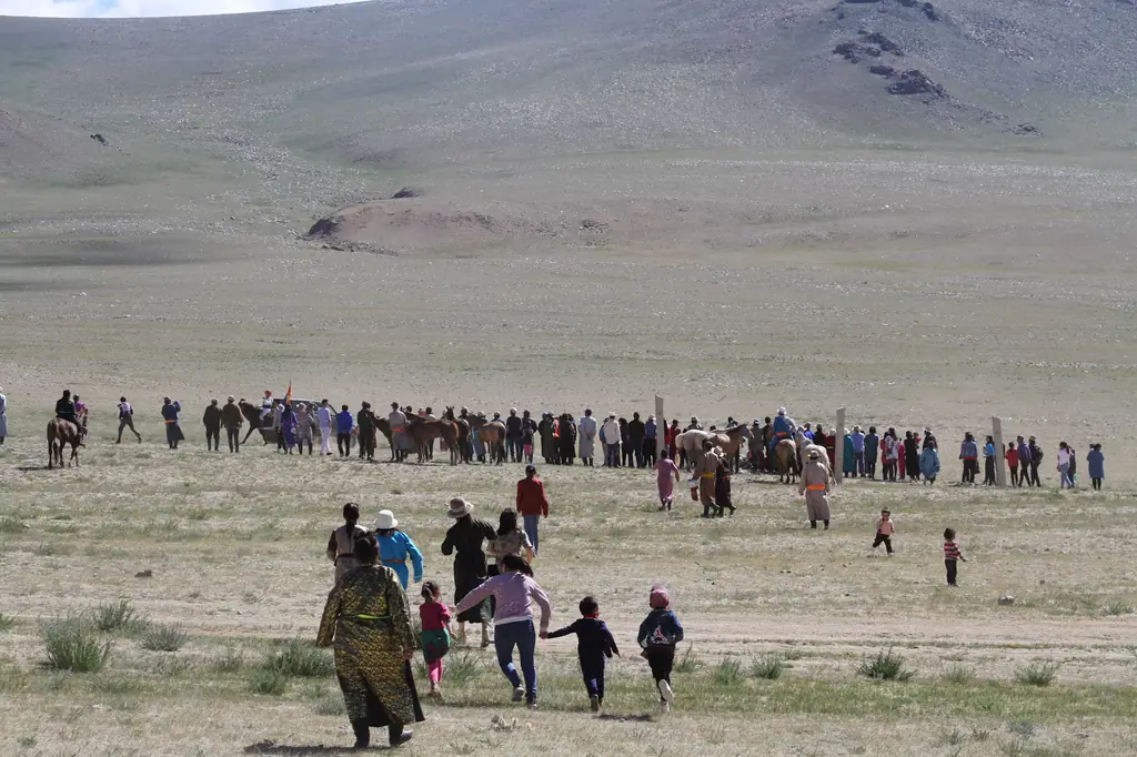 Families run to meet the riders at a local naadam horse race